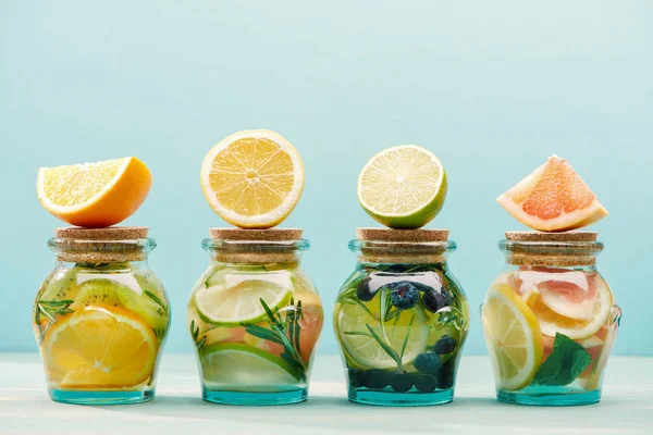 Fresh detox drinks in jars with ingredients isolated on blue — Stock Photo