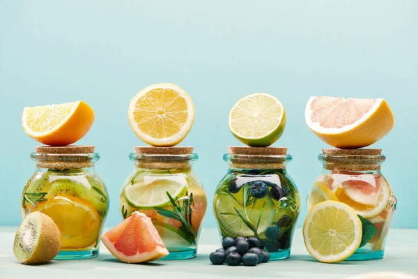 Fresh detox drinks in jars with ingredients isolated on blue — Stock Photo