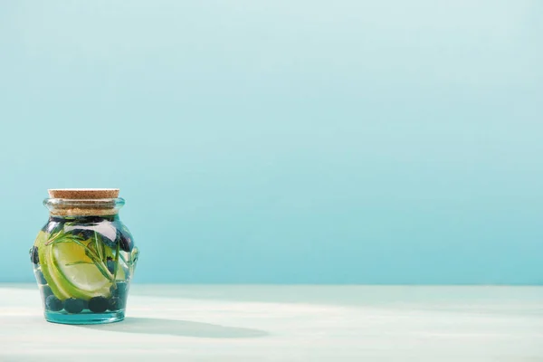 Entgiftungsgetränk im Glas mit Rosmarin, Blaubeeren, Limetten auf blauem Grund — Stockfoto