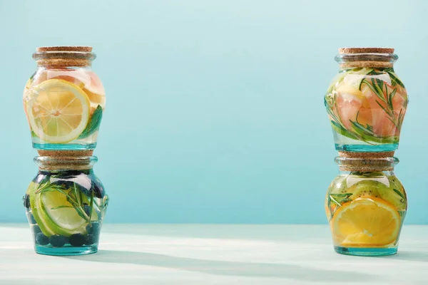 Детоксикационные напитки в банках со свежими фруктами, изолированными на голубом — стоковое фото