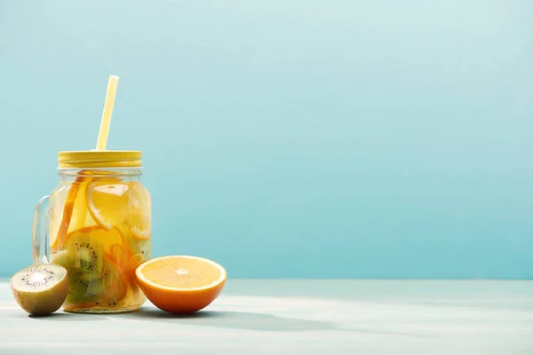 Bio-Entgiftungsgetränk im Glas mit Stroh in der Nähe von Orange und Kiwi isoliert auf blau — Stockfoto