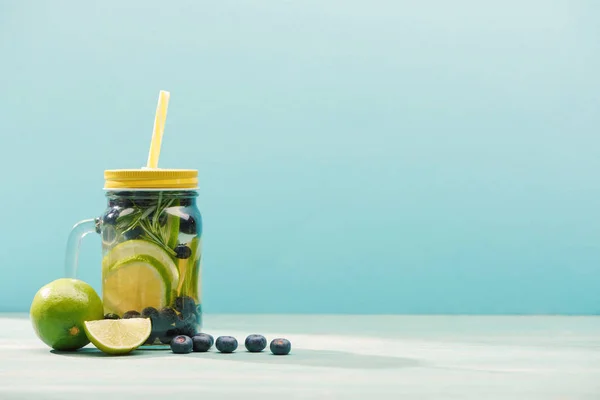 Boisson de désintoxication fraîche dans un bocal avec de la paille près de bleuets et de tilleuls isolés sur bleu — Photo de stock