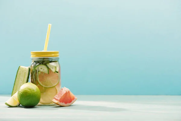 Bebida de desintoxicação fresca em jarra perto de limas, pepino e toranja isolados em azul — Fotografia de Stock