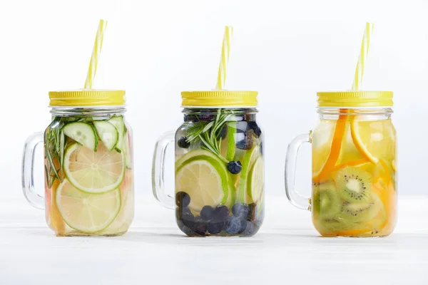 Frische Detox-Getränke in Gläsern mit Strohhalmen, Früchten und Beeren auf weißem Hintergrund — Stockfoto