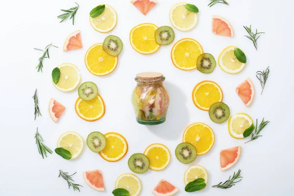 Flache Lage mit frisch geschnittenen Kiwi, Orangen, Zitronen, Grapefruits, Minze, Rosmarin und Entgiftungsgetränk im Glas — Stockfoto