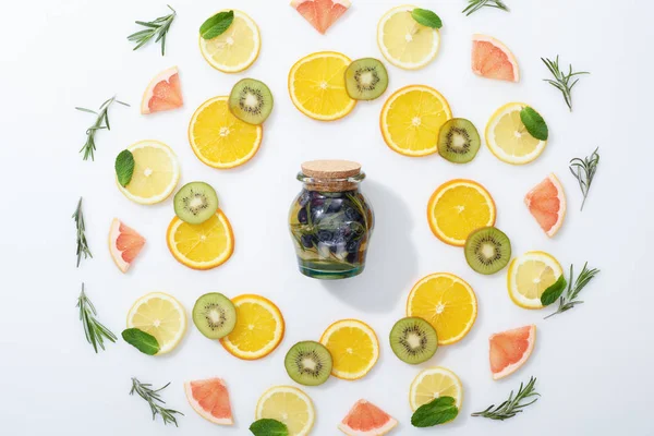 Flat lay with sliced kiwi, oranges, lemons, grapefruits, mint, rosemary and detox drink in jar — Stock Photo