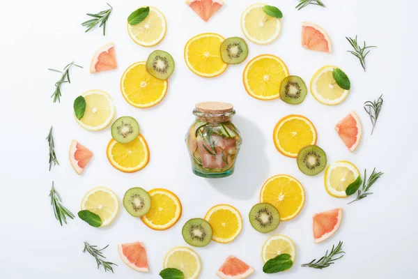 Flat lay with sliced kiwi, oranges, lemons, grapefruits, mint, rosemary and fresh detox drink in jar on grey background — Stock Photo