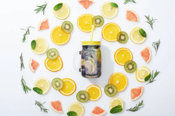 Flat lay with sliced kiwi, oranges, lemons, grapefruits, mint, rosemary and detox beverage in jar on grey background — Stock Photo