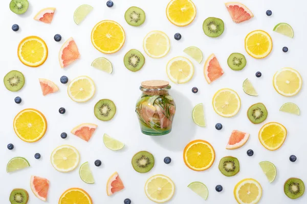 Vue du dessus de la boisson de désintoxication en pot parmi les fruits tranchés et les bleuets sur fond blanc — Photo de stock