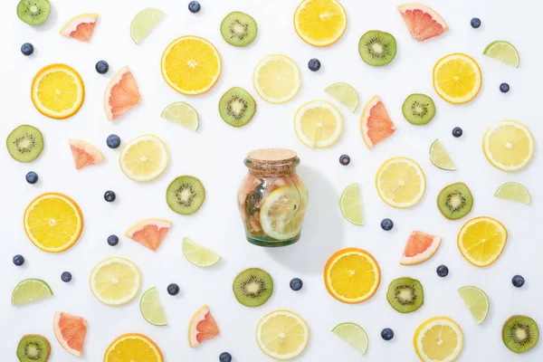 Vista superior da bebida de desintoxicação orgânica no frasco entre frutas fatiadas e mirtilos no fundo branco — Fotografia de Stock