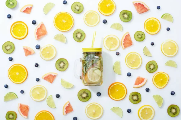 Vista dall'alto della bevanda disintossicante in vaso con paglia tra frutta e mirtilli su fondo bianco — Foto stock