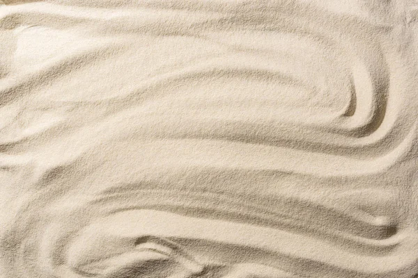 Vue de dessus du fond beige sable texturé avec des vagues lisses — Photo de stock