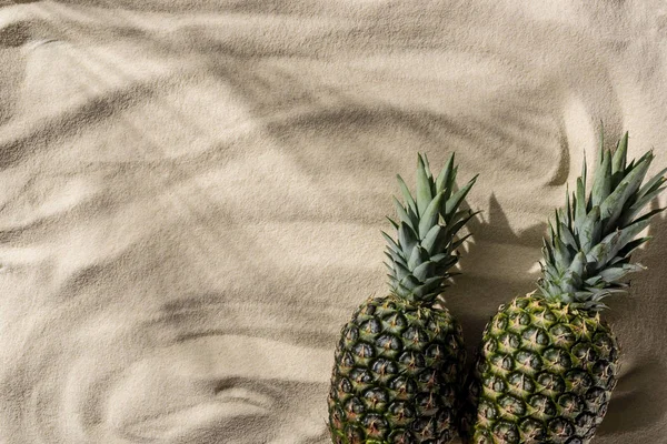 Vue de dessus des ananas frais sur sable texturé avec espace de copie — Photo de stock