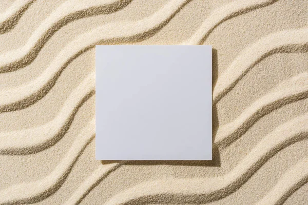 Top view of sandy background with smooth waves and blank card — Stock Photo