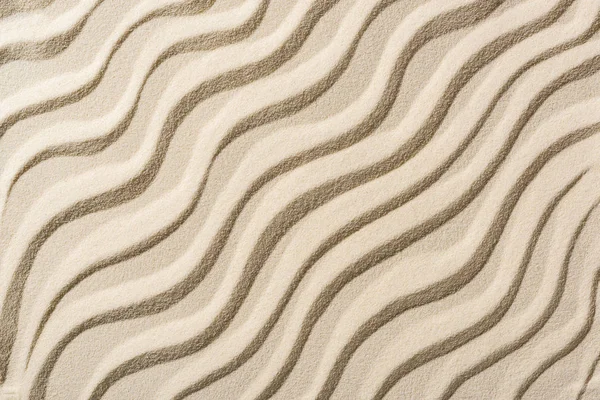 Вид сверху на бежевый песчаный фон с гладкими волнами — стоковое фото