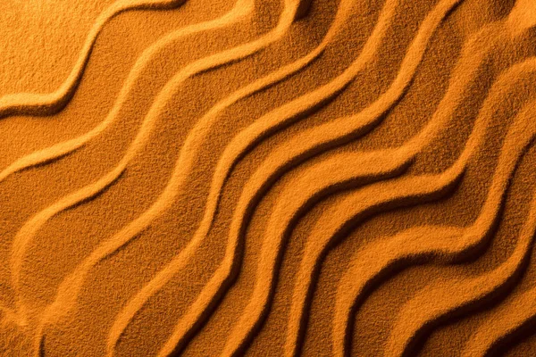 Top view of sandy background with smooth waves and orange color filter — Stock Photo