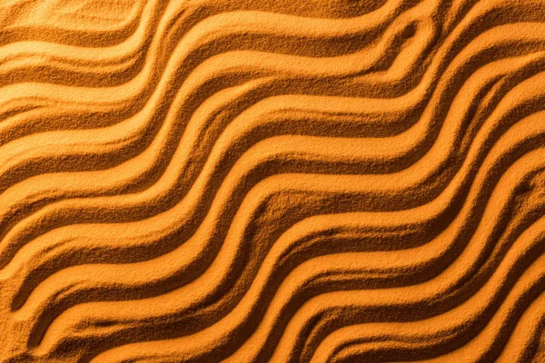 Top view of sandy background with smooth waves and orange color filter — Stock Photo