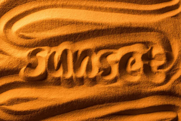 Top view of word sunset written in sand with smooth waves and color filter — Stock Photo