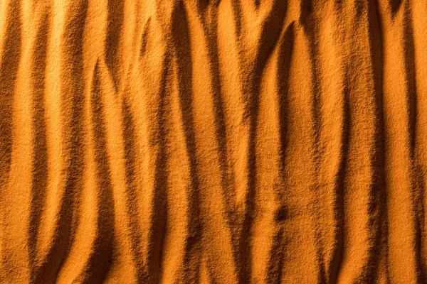 Вид сверху на текстурированный пляжный песок с волнами и оранжевым цветом фильтра — стоковое фото