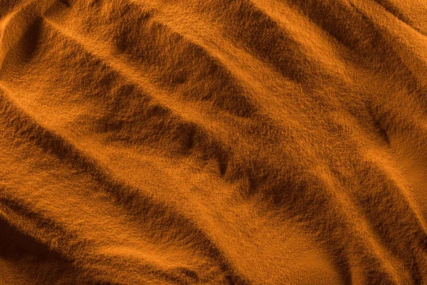 Top view of textured sand with smooth waves and orange color filter — Stock Photo