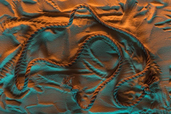 Top view of bend rope and traces of rope on the sand with orange and blue lights — Stock Photo