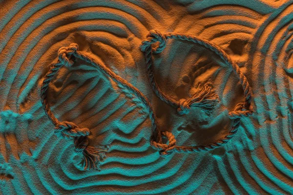 Top view of arc lines traces of rope and ropes with knots on sand with orange and blue lights — Stock Photo