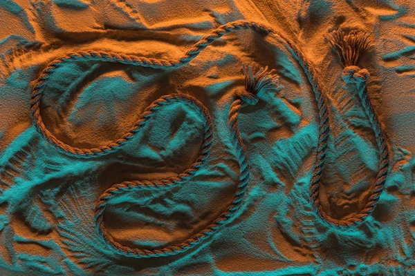 Верхний вид изогнутой веревки и следы веревки в песке с оранжевым и синим огнями — Stock Photo