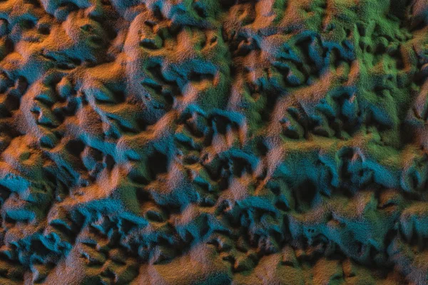 Top view of textured sand with orange, green and blue lights — Stock Photo