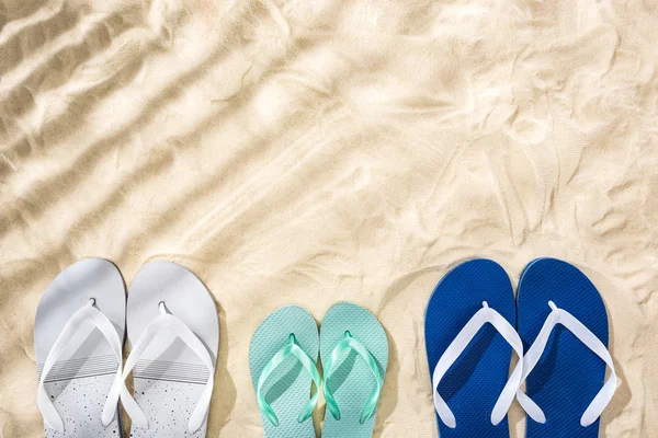 Vista superior de blanco, turquesa y blanco azul chanclas en la arena con sombras y espacio de copia - foto de stock