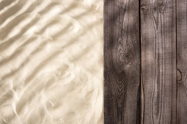 Vista superior de arena texturizada y tablero marrón de madera con espacio de copia - foto de stock