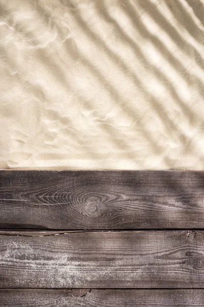 Vista superior de arena con sombras y tablero marrón madera con espacio de copia - foto de stock