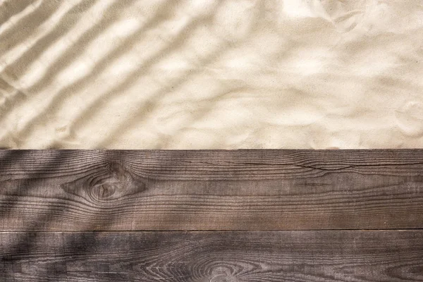 Vista superior de arena y tablero marrón de madera con sombras y espacio de copia - foto de stock