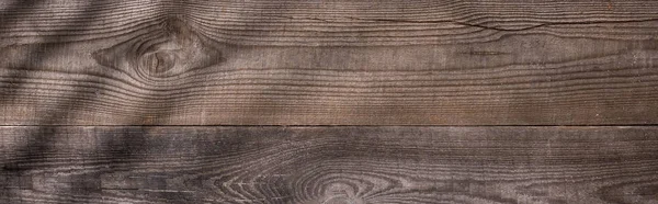 Panoramic shot of wooden brown board with shadows and copy space — Stock Photo