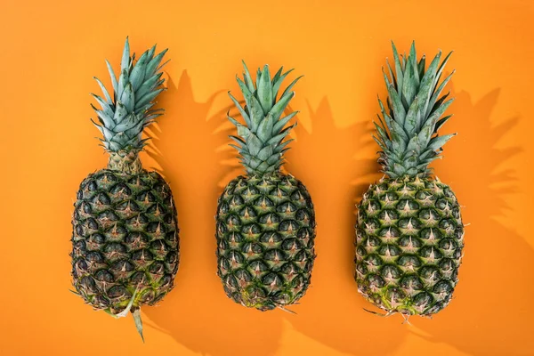 Top view of pineapples with side shadows on orange background — Stock Photo