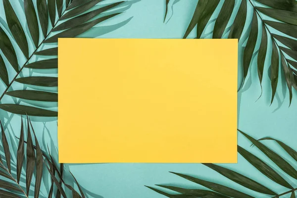 Top view of tropical leaves and empty yellow card on turquoise background — Stock Photo