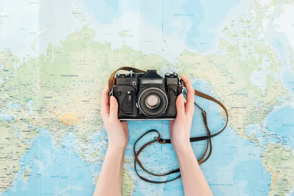 Vista cortada da mulher segurando câmera de filme no mapa do mundo — Fotografia de Stock