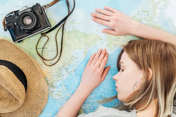 Mujer con cámara de cine y sombrero de paja durmiendo en el mapa del mundo - foto de stock