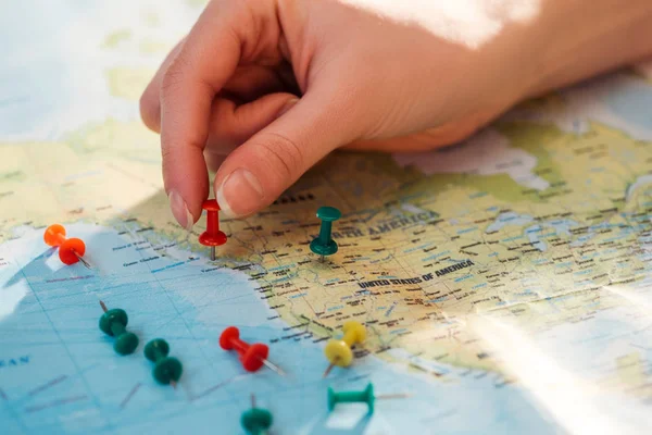 Partial view of woman and colorful push pins on world map — Stock Photo