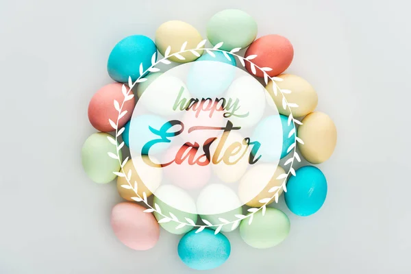 Vista superior de ovos multicoloridos pintados com letras brancas de Páscoa felizes em círculo — Fotografia de Stock