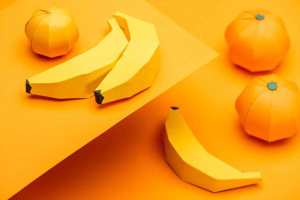 Selective Focus of origami bananas and tangerines on orange — Stock Photo