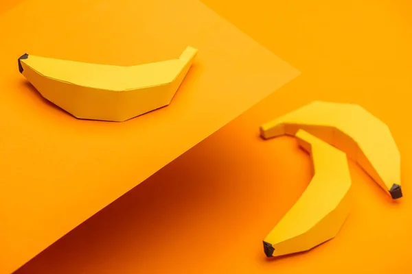 Fondo con plátanos hechos a mano en origami sobre papel naranja - foto de stock