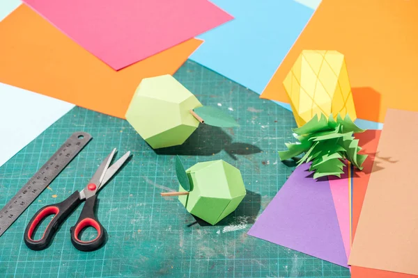 Origami fruits et carton coloré avec ciseaux et règle sur surface salissante — Photo de stock
