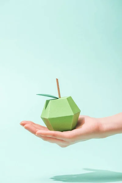 Cropped view of young woman holding handmade paper apple on turquoise with copy space — Stock Photo