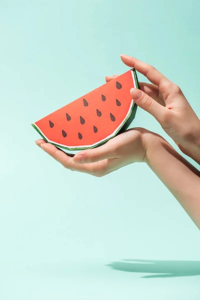 Abgeschnittene Ansicht einer jungen Frau, die Papierwassermelone mit Samen auf Türkis hält — Stockfoto