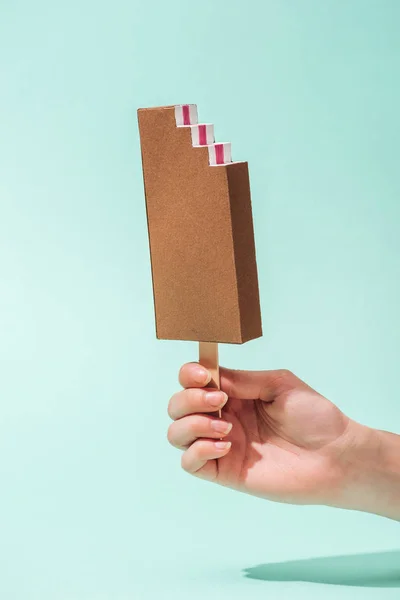 Cropped view of young woman holding paper ice cream on turquoise — Stock Photo