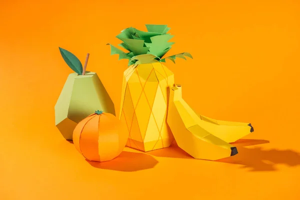 Papel hecho a mano piña, plátanos, pera y mandarina sobre naranja - foto de stock