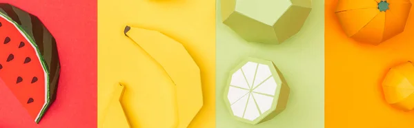 Plano panorámico de origami sandía, plátanos, mandarinas y limas sobre papel a rayas de colores - foto de stock