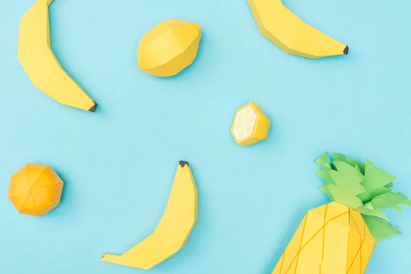 Вид зверху паперові лимони ручної роботи, банани та ананаси ізольовані на синьому — стокове фото