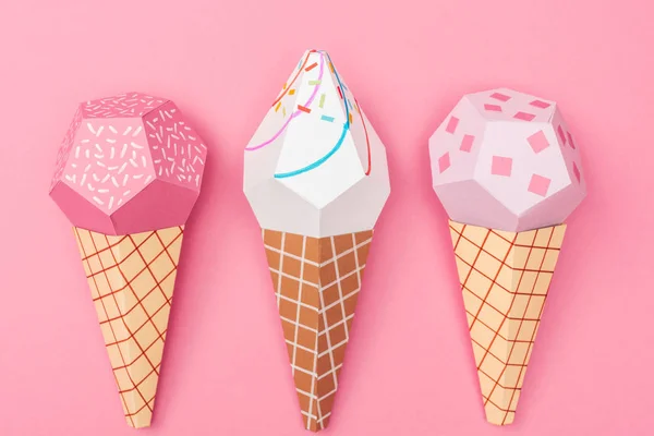 Vue du dessus de cônes de crème glacée origami coloré faits à la main isolés sur rose — Photo de stock