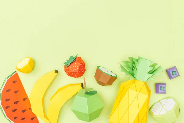 Vista superior de frutas de origami coloridas hechas a mano aisladas en verde con espacio para copiar - foto de stock